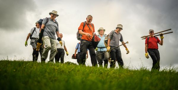 A group of Ramblers path maintenance volunteers walking across a field
